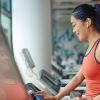woman with earbuds taps on treadmill screen